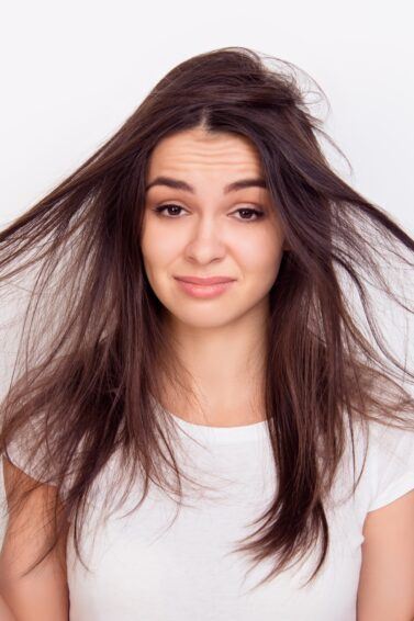 Mulher morena segura o cabelo danificado por química