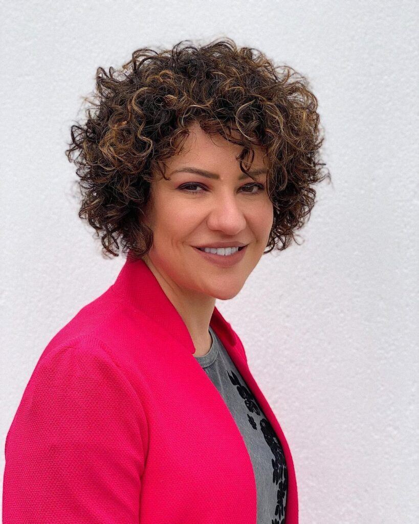 mulher sorrindo com cabelo cacheado curto em camadas