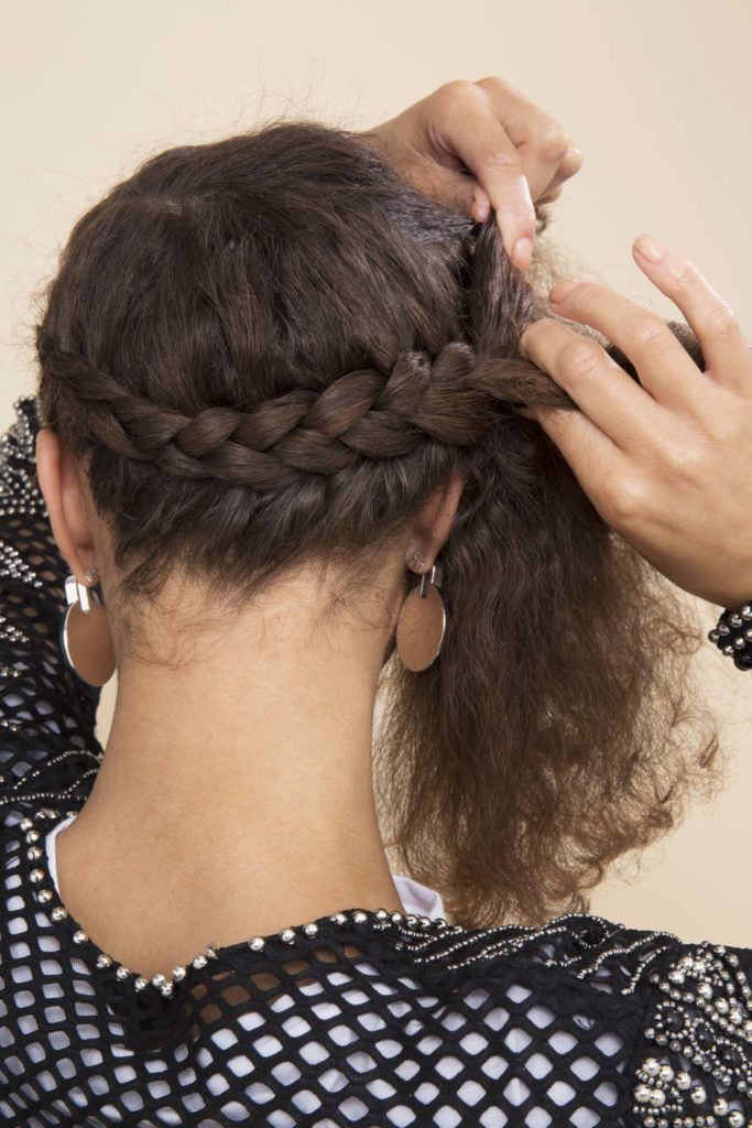 mulher trançando o cabelo sozinha