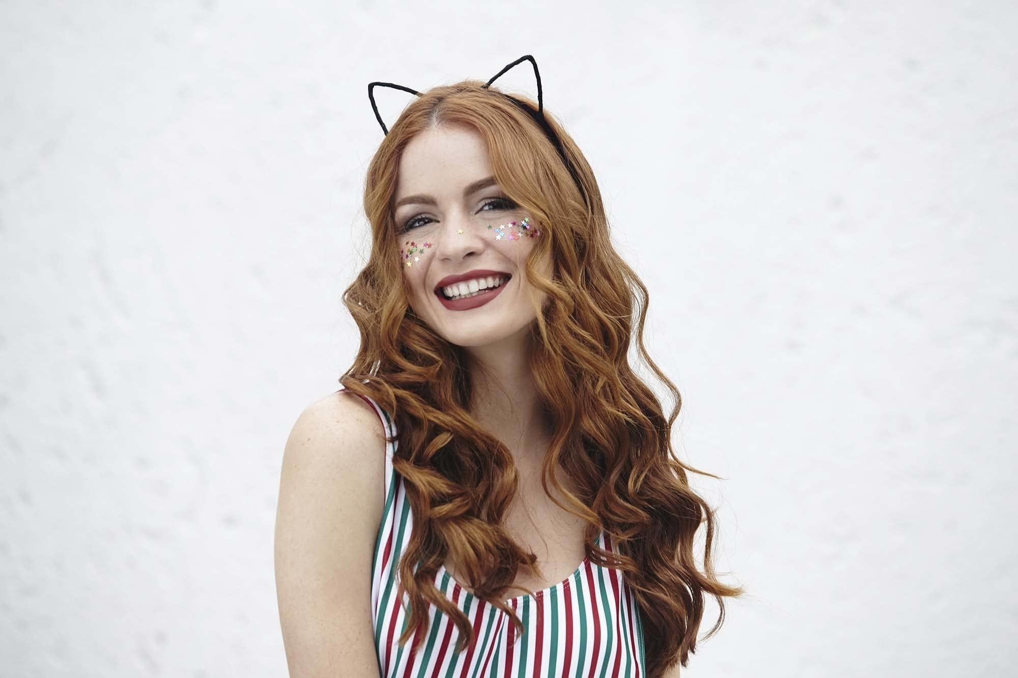 modelo com cabelo longo ondulado e tiara de gatinho para matéria de cuidados com a peruca