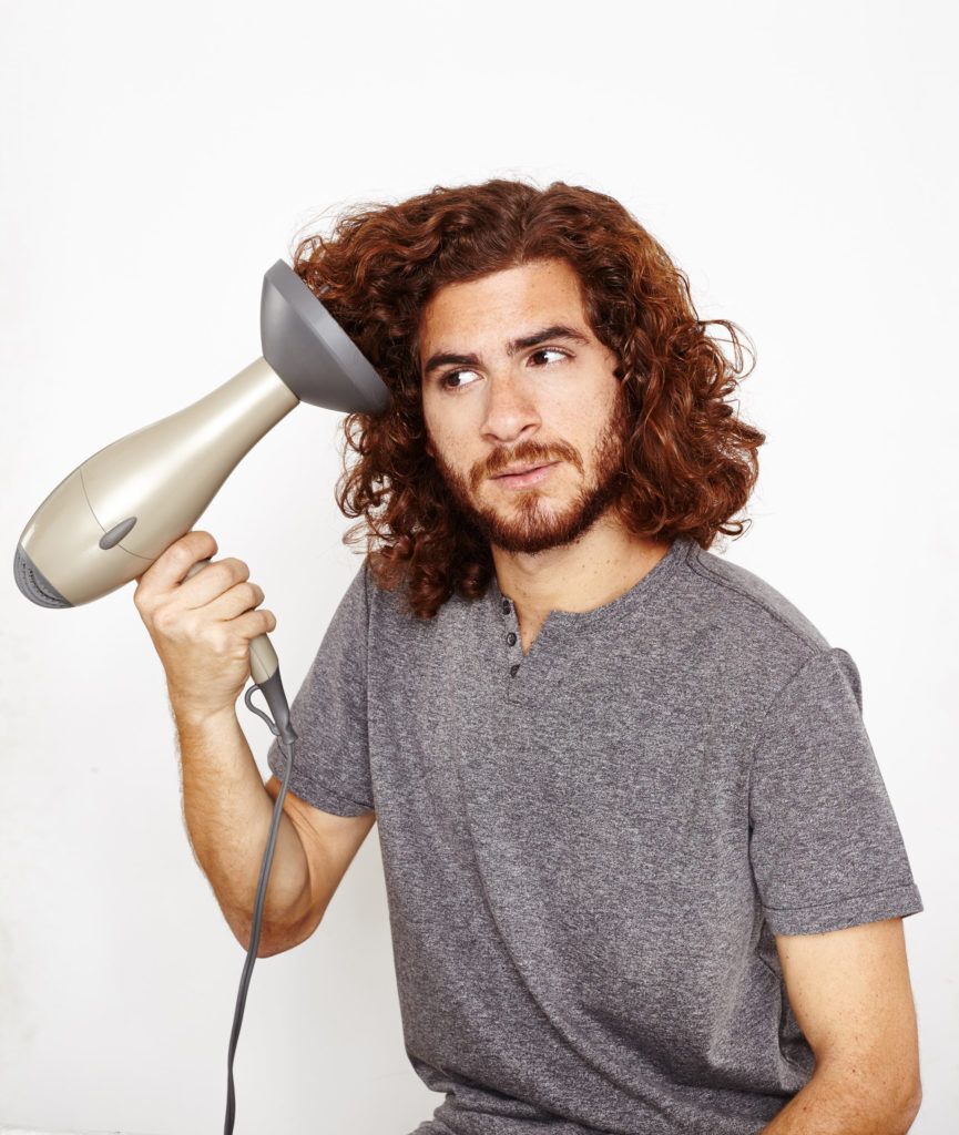 Homem usa secador com difusor para definir cachos no cabelo masculino
