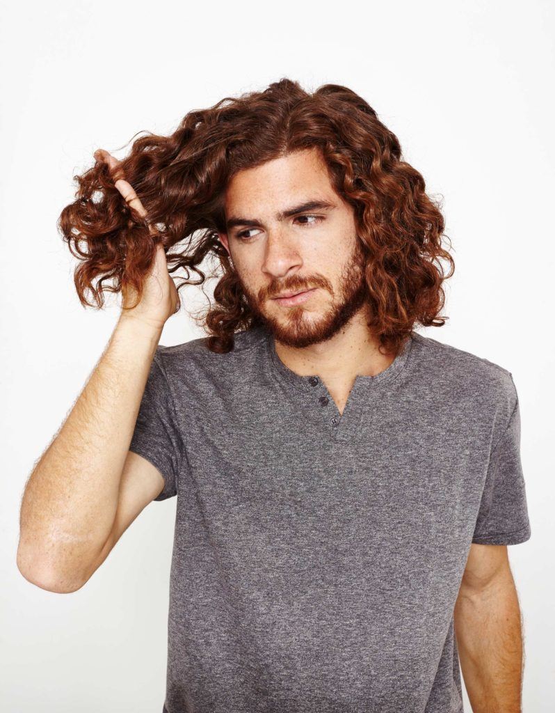 Homem passa os dedos no cabelo depois de definir cachos no cabelo masculino