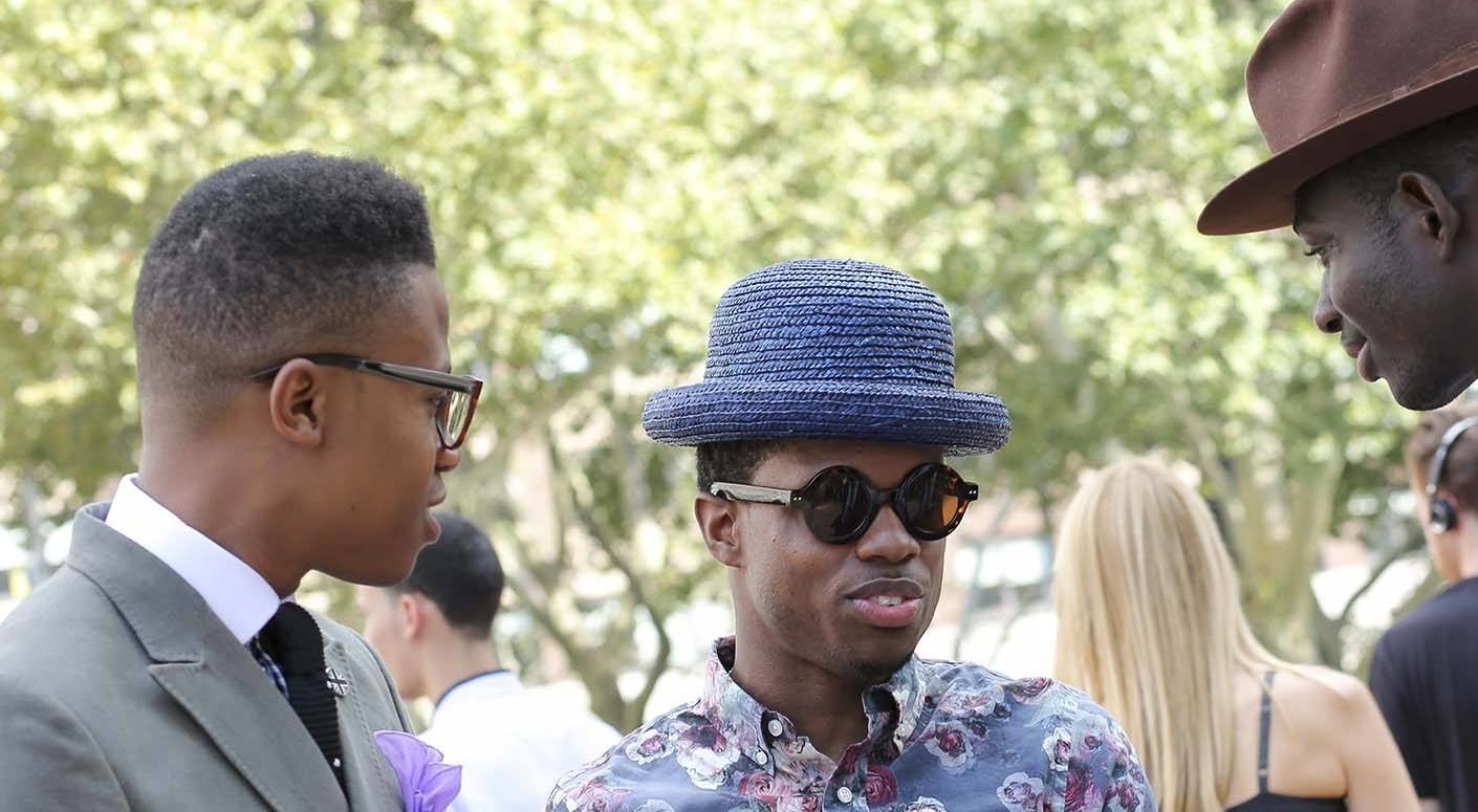 Três homens estão na foto e um deles, à esquerda, usa high top fade