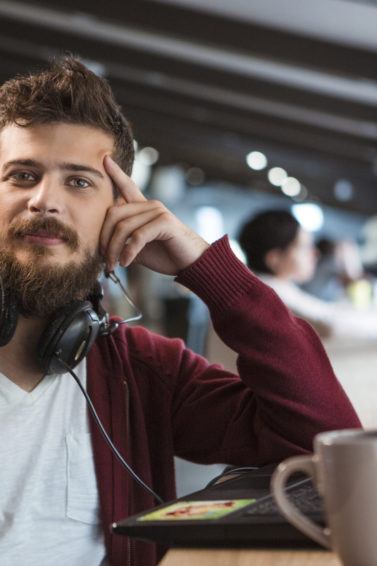 Homem toma café e encara a câmera com cabelo estilo nerd