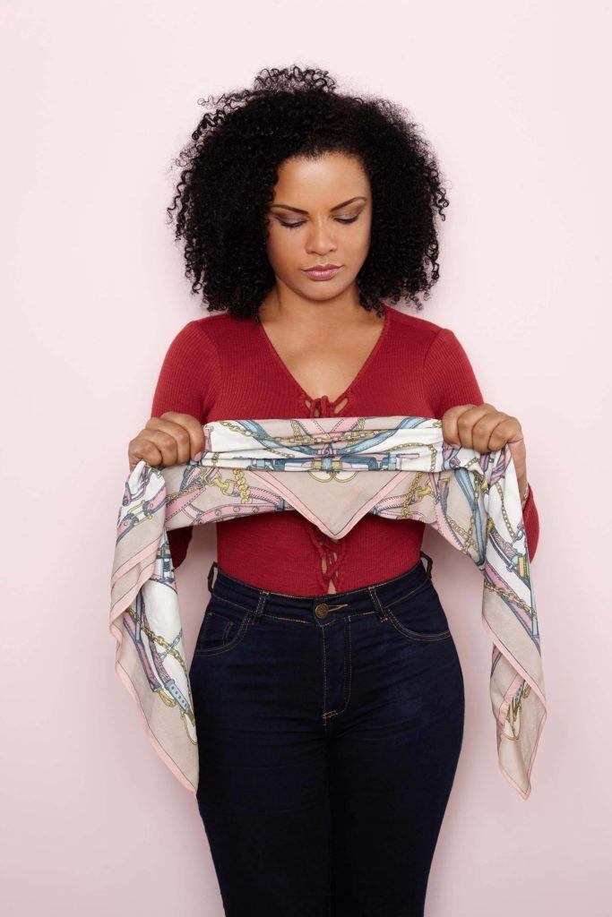 Mulher com cabelo afro segurando um lenço