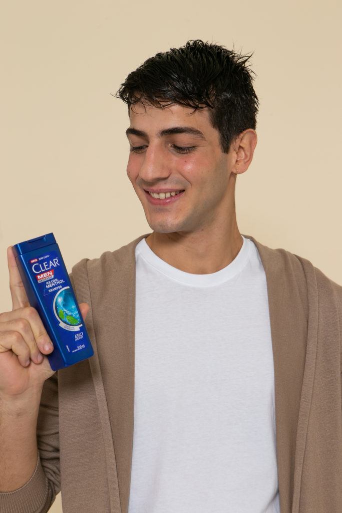 Modelo com o cabelo molhado segurando o shampoo para ensinar como secar o cabelo