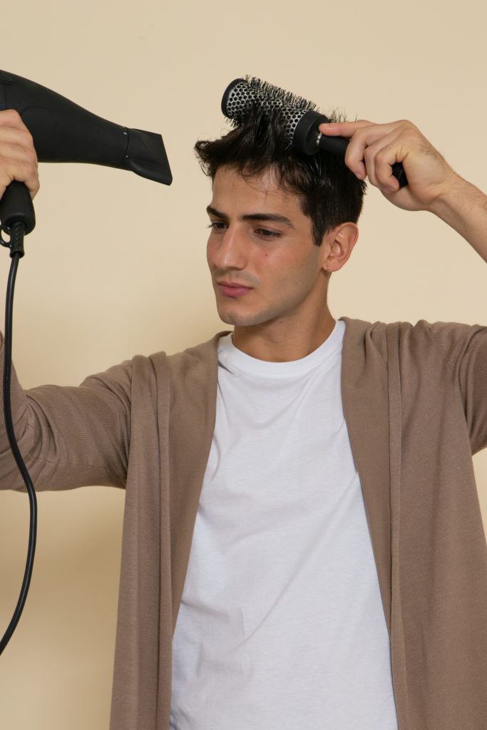 Modelo usa o secador e a escova para ensinar como secar cabelo masculino