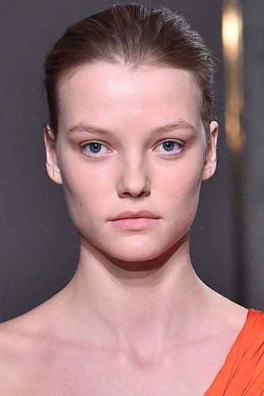 Mulher desfila com coque e vestido laranja