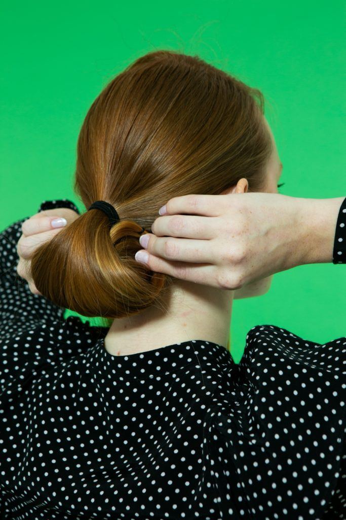 Modelo faz rolinho no cabelo em passo a passo para fazer coque chignon