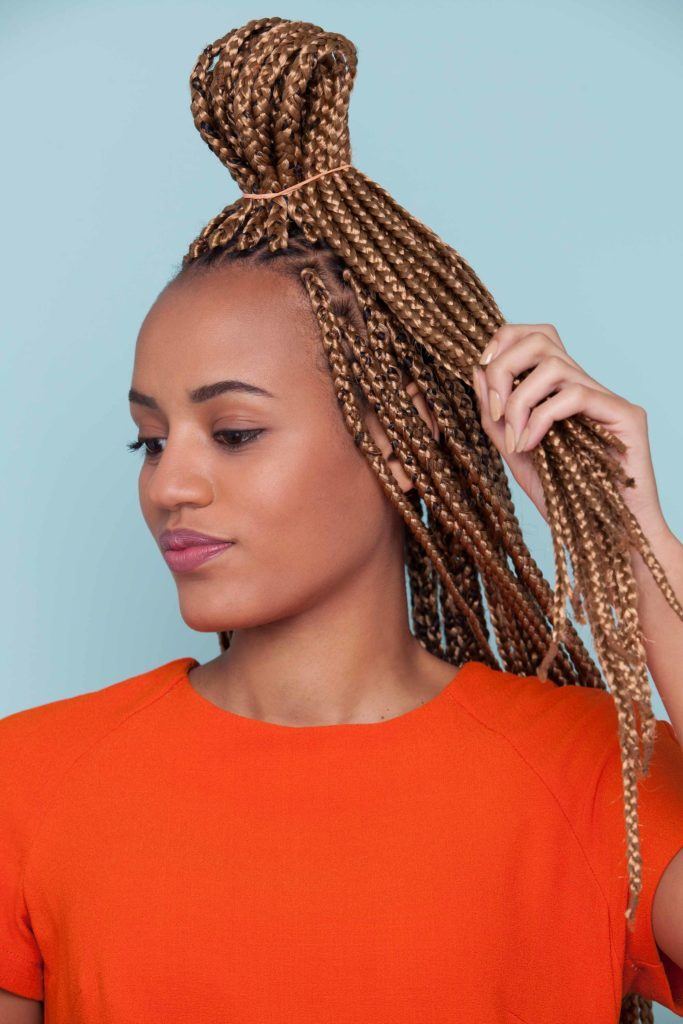 Mulher fazendo coque de lanço no cabelo trançado