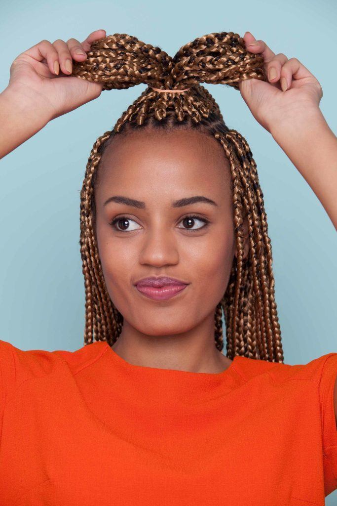 Mulher fazendo coque de lanço no cabelo trançado