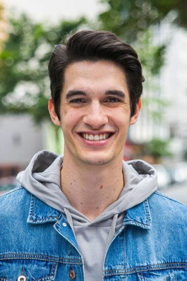Homem com jaqueta eans e moletom com cabelo penteado para o lado e topete
