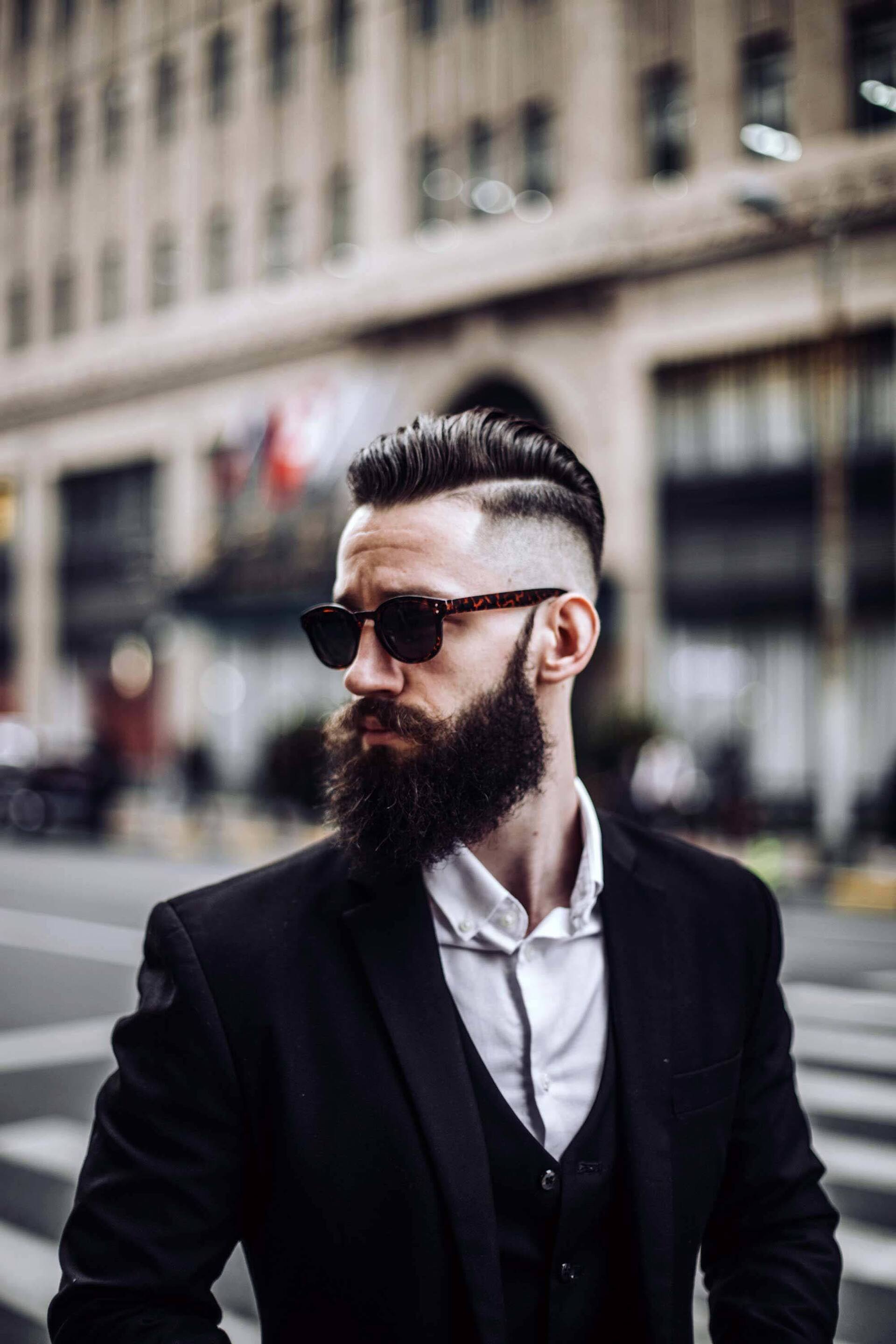 Homem com cabelos e barba pretos e fios raspados na lateral