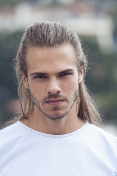 homem loiro de cabelo comprido mostra como estilizar o cabelo masculino