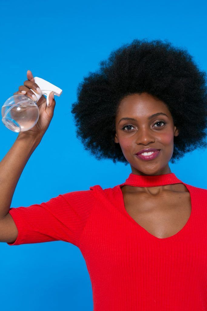 modelo de cabelo afro borrifando água no cabelo.
