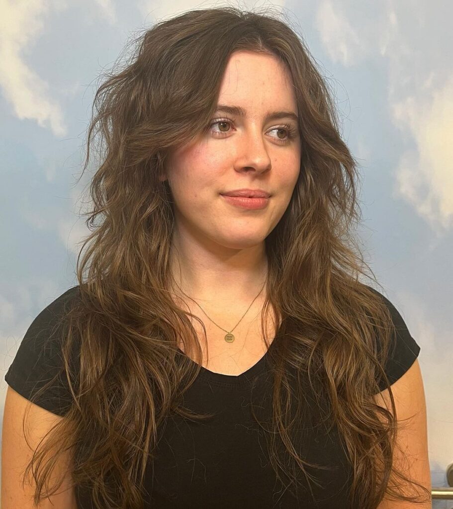 Mulher em fundo azul com mullet feminino longo no cabelo castanho ondulado estilo cabelo polvo ou octopus hair