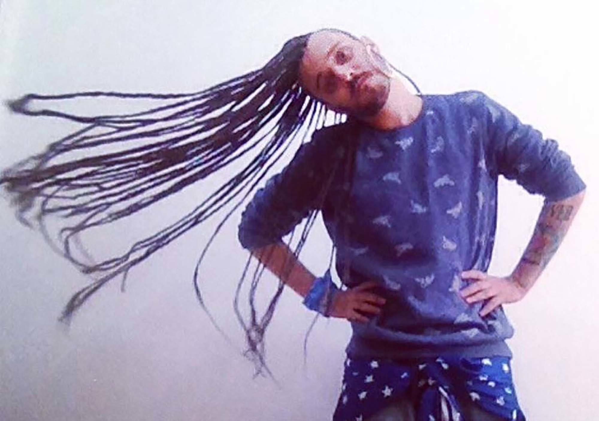 homem branco usa dreads longos e roupa azul marinho.