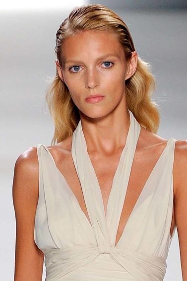 Mulher loira usa vestido branco e raiz com gel e cabelo ondulado