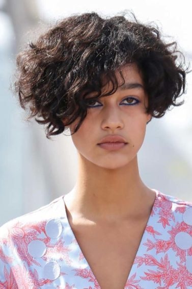 Modelo desfila com roupa floral branca e rosa e o cabelo amassado, um dos ondulados para testar. técnica capilar das 12 proteínas.