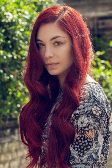 Mulher de cabelo vermelho mostra que ruivo combina com pele morena