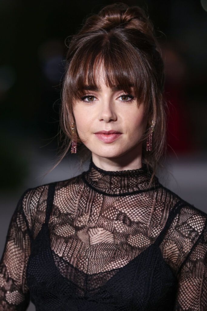 atriz lily collins com coque combinado com franja bardot