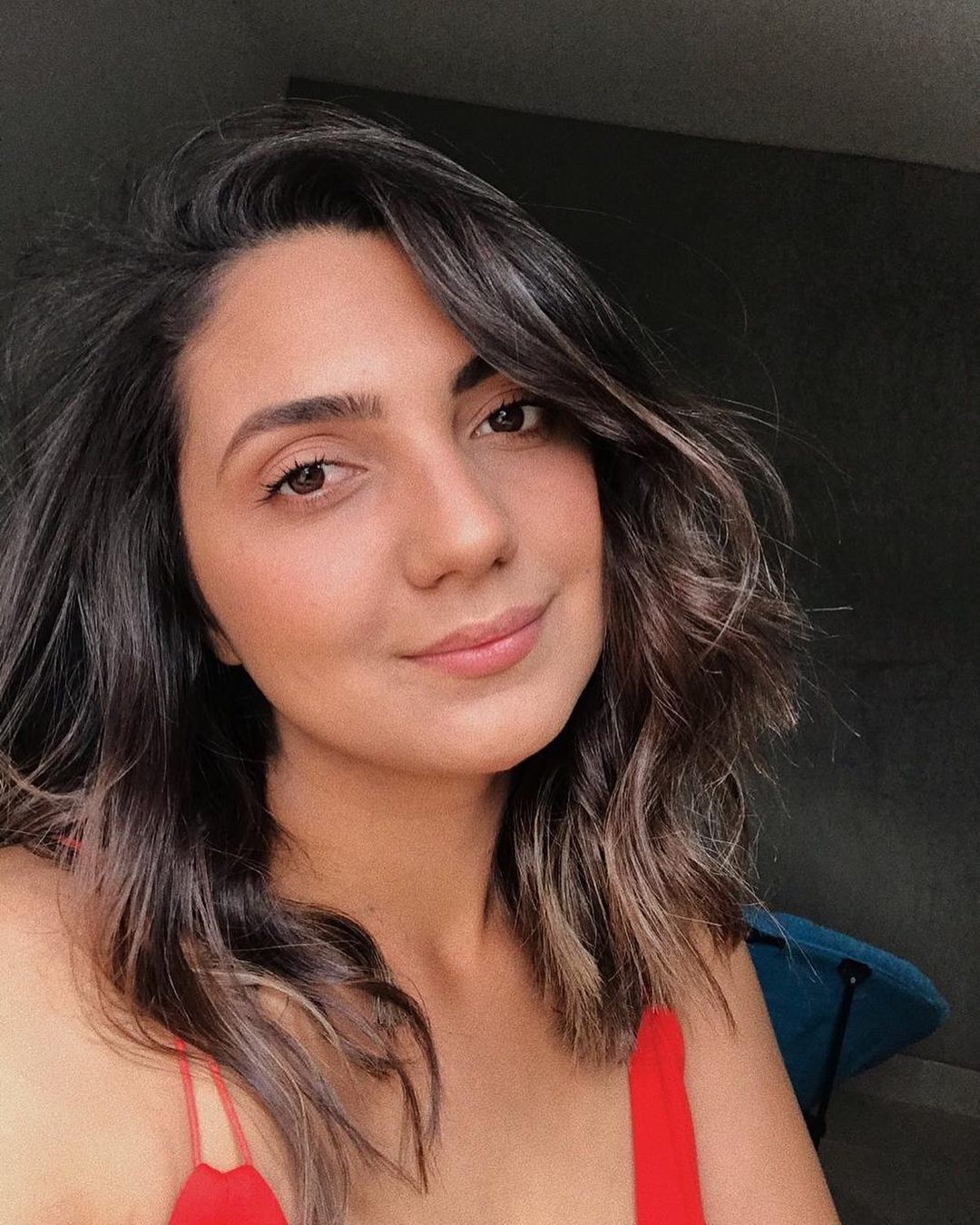mulher com franja longa de lado e camiseta vermelha