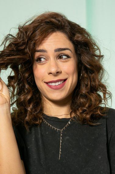 mulher segura mecha de cabelo e olha para ele com cara de dúvida