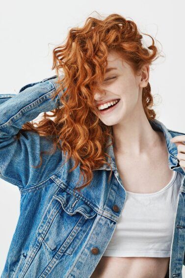 mulher ruiva sorrindo mexendo no cabelo