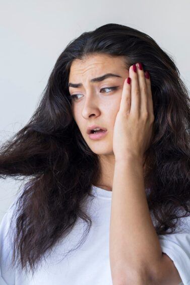 Mulher olhando para o cabelo preocupada em como saber se o cabelo está danificado