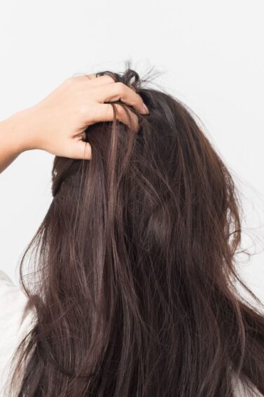 mulher de costas coçando o cabelo