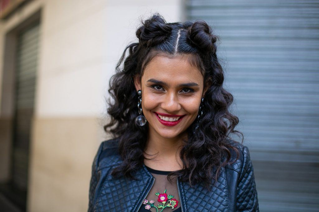 Modelo com cabelos pretos e penteado semipreso com coque duplo para o Coala Festival