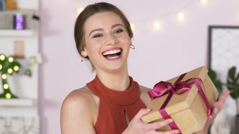 modelo com coque e vestido vermelho recebe presente de Natal