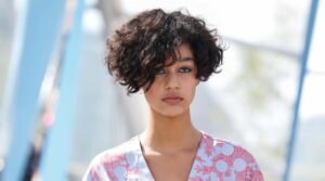 Modelo desfila com quimono branco e rosa e usa cachos nas pontas do cabelo branco