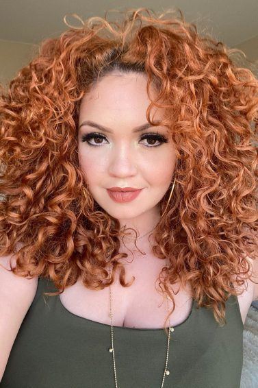 ruiva com cabelo cacheado e raiz aparente