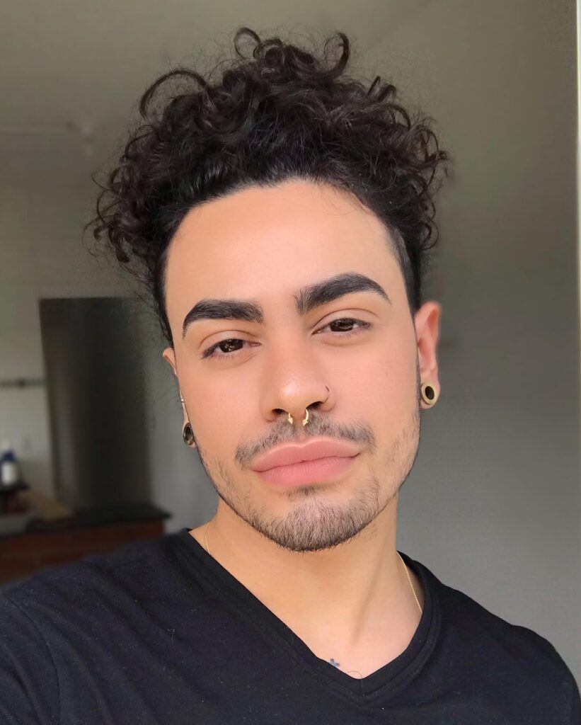 homem com cabelo cacheado preso em coque