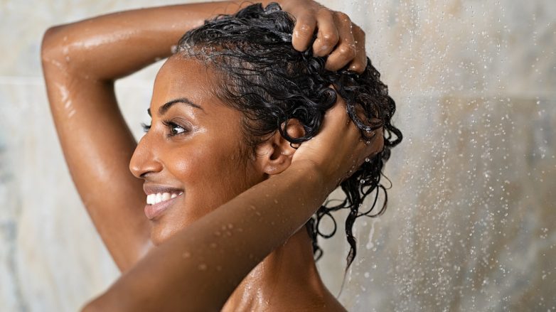 Mulher lava os cabelos cacheados com a técnica no poo