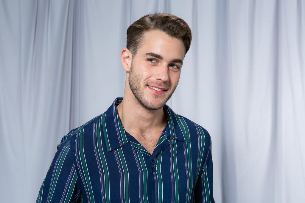 Homem com cabelo dividido na lateral com topete e leve sorriso