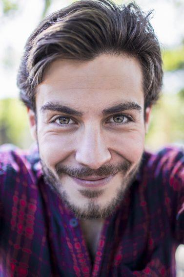 Homem com cabelos castanho-claros jogados para o lado em pose de selfie