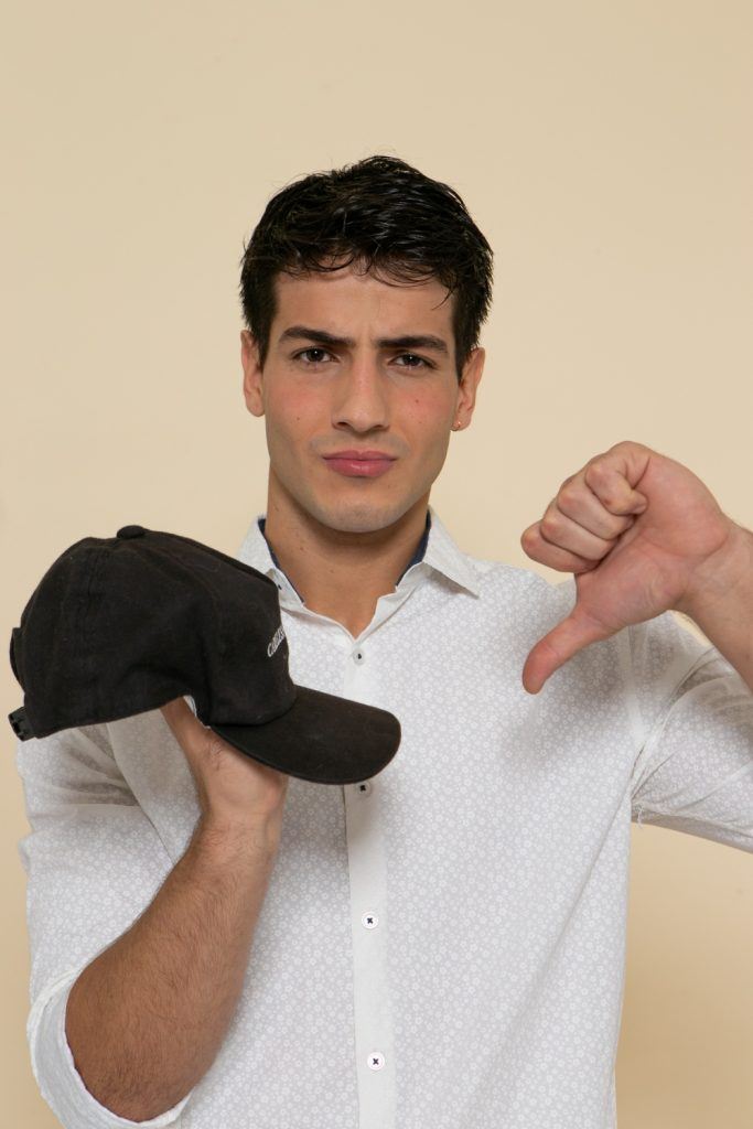 modelo masculino de cabelo liso e preto exibindo cuidado com cabeludo masculino e mostrando um boné