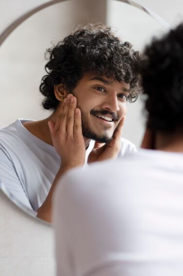 homem com barba se olhando no espelho