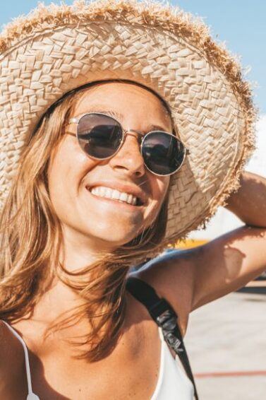 mulher loira com chapéu tirando selfie em frente a um avião