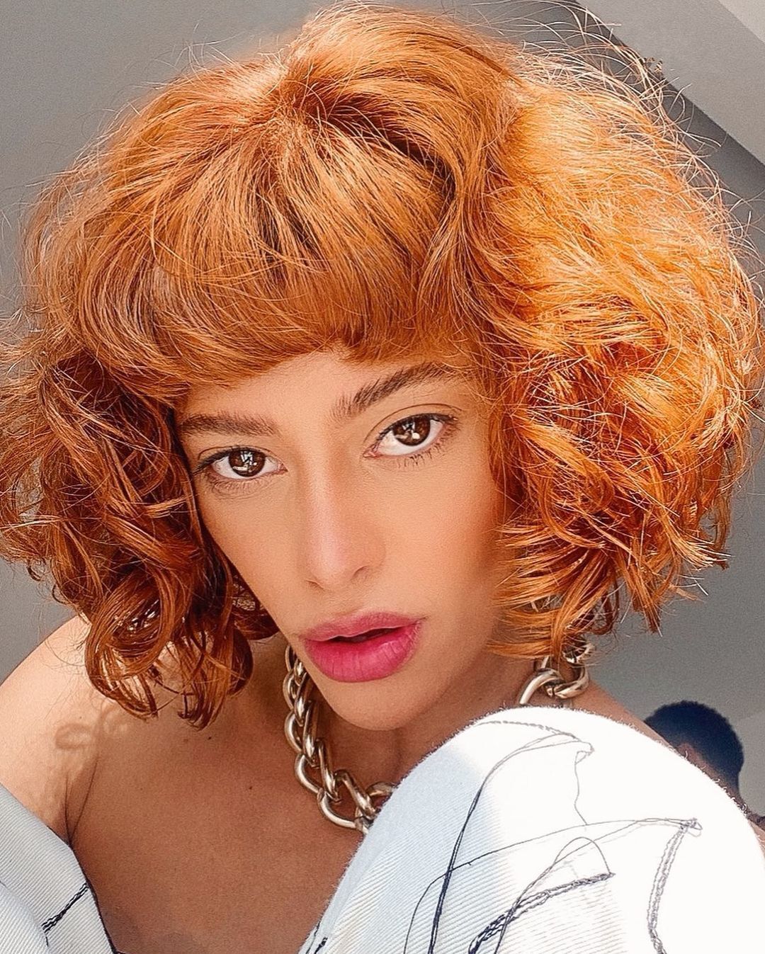 Mulher com franja no cabelo ruivo e cacheado