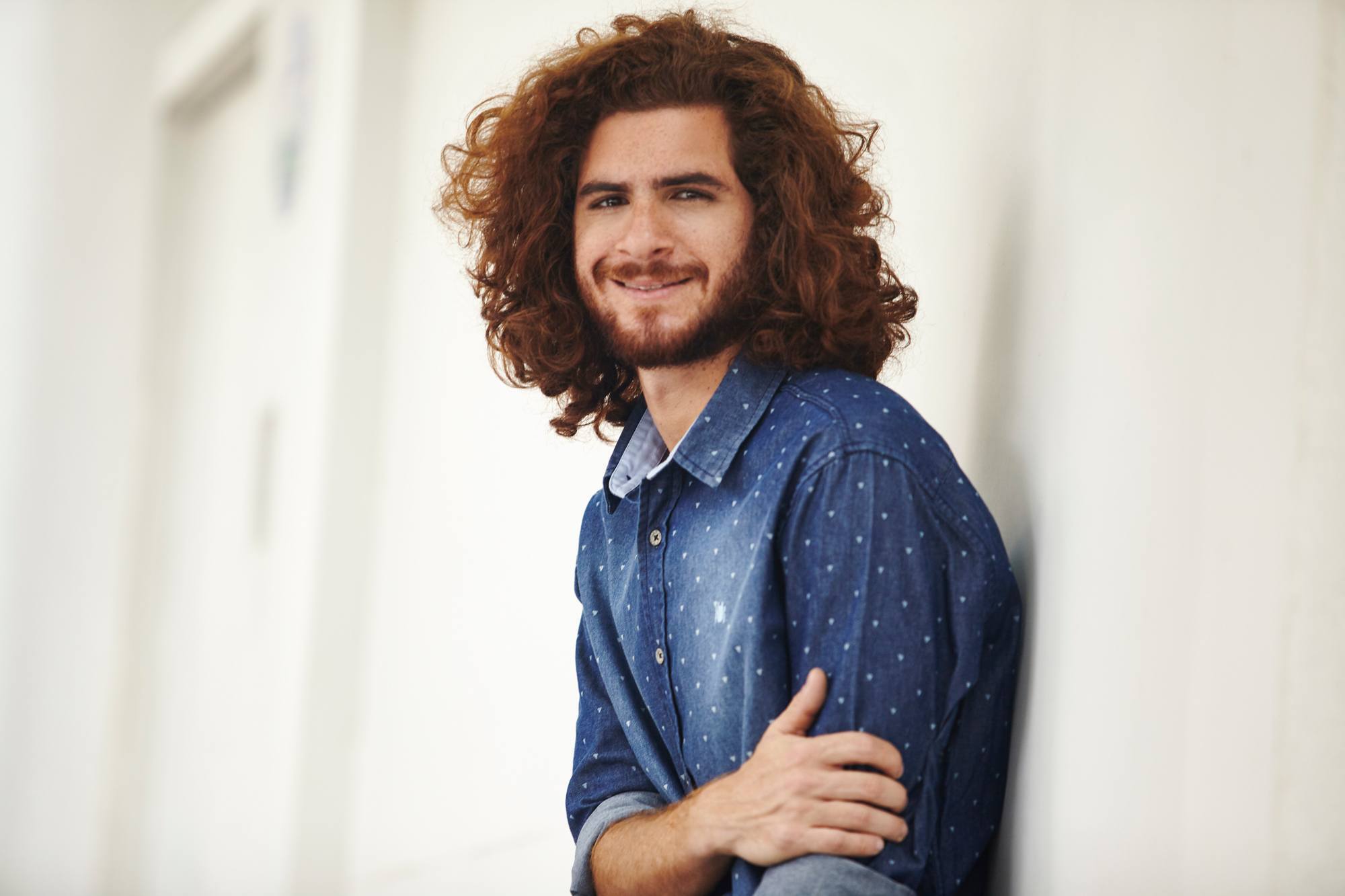 Modelo com cabelo longo ruivo cacheado usando amisa jeans