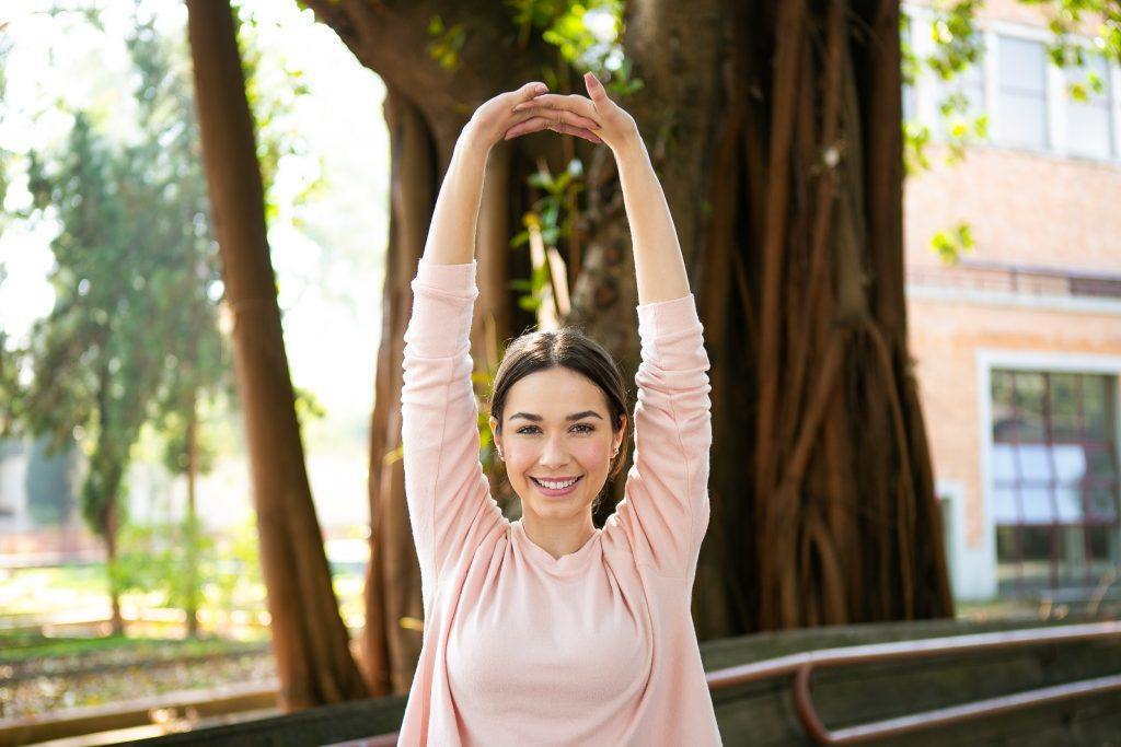 Modelo com cabelos castanhos faz alongamento para yoga