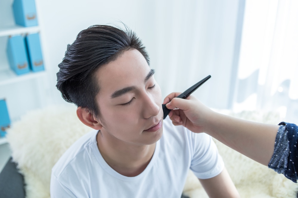 男性の顔にメイクをしている様子。