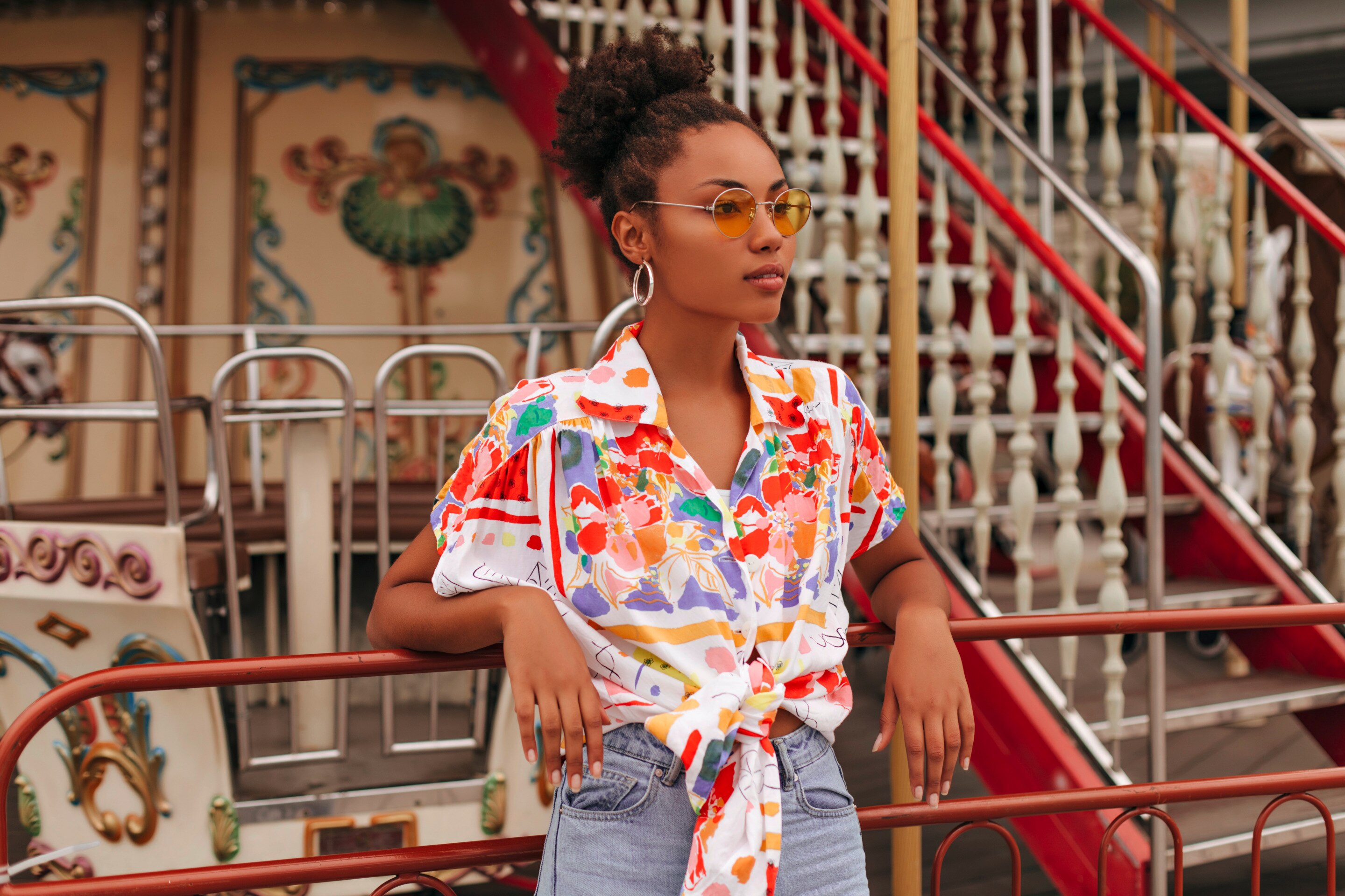 ผู้หญิงผิวสี ใส่เชิ้ต พื้นขาว ลายพิมพ์ดอกไม้หลากสี ยืนพิงขอบลูกกรงระเบียงเรือ