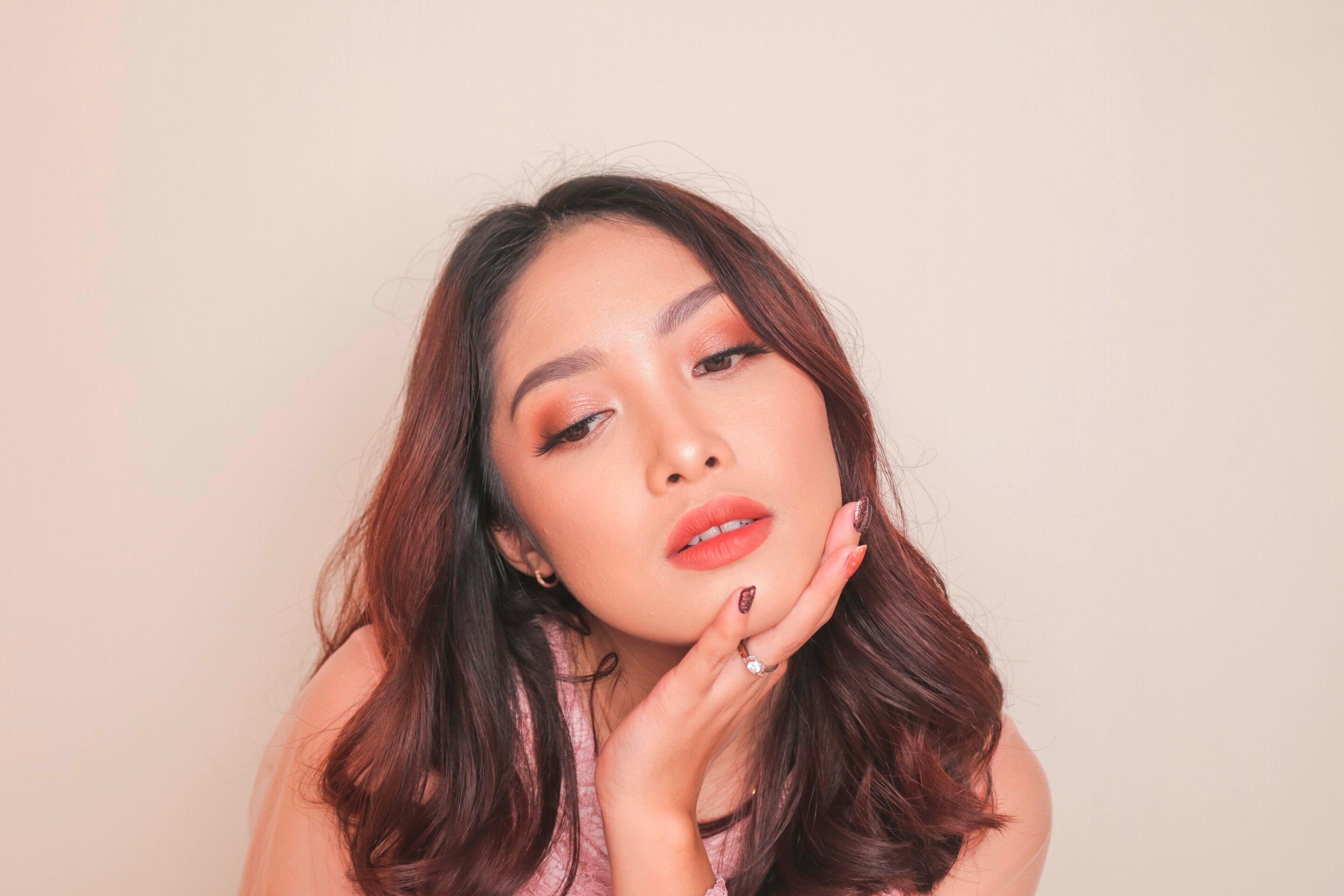 สาวเอเชีย แต่งหน้าโทนสีส้ม มือจับคาง