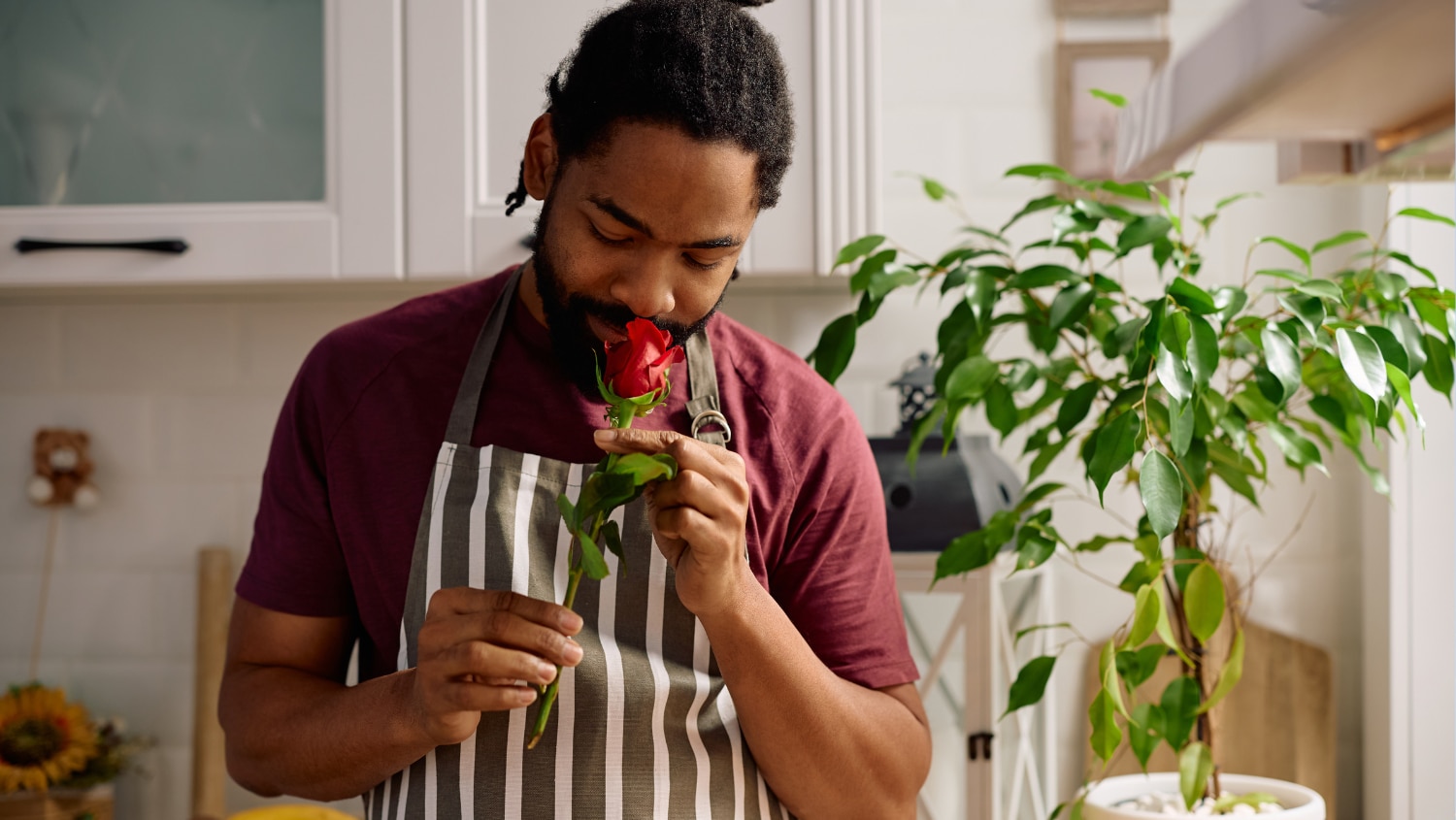 Young man smelling a red rose trying to find the best smelling scent for him