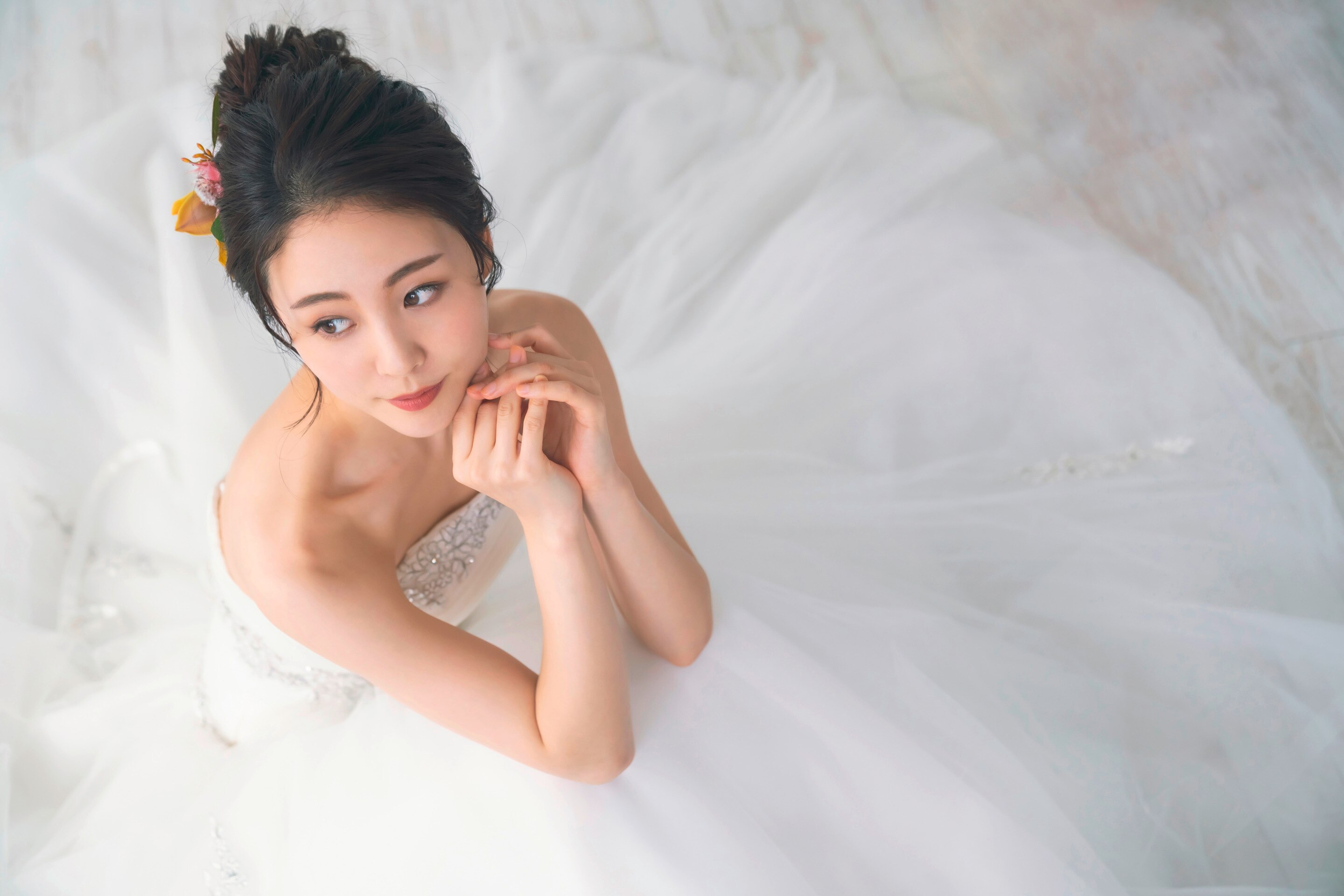 เจ้าสาว ใส่ชุดแต่งงาน ชุดราตรี กำลังนั่ง ทำผมเจ้าสาวแบบ glam ติดเครื่องประดับ ดอกไม้