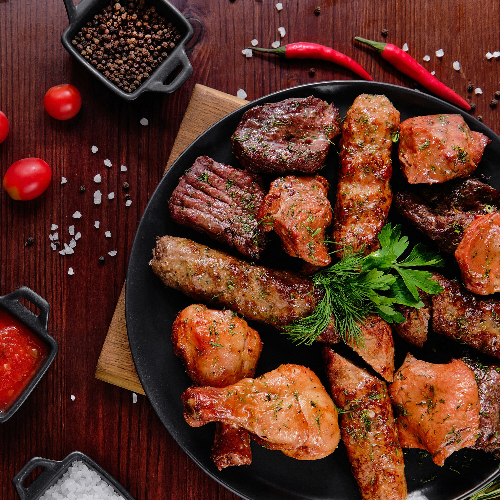 Meat on a black plate with a tomato dipping sauce on the side